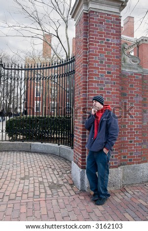 a student takes a smoke break at the gates of an American university on a gloomy winter day