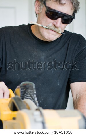 a carpenter concentrating on making the correct cut - focus on mouth in concentration