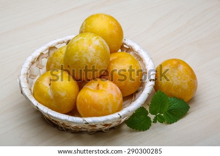 Yellow plums in the basket on wood