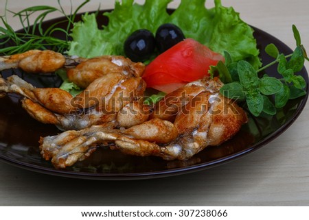 Fried frog legs with olive, herbs and spices