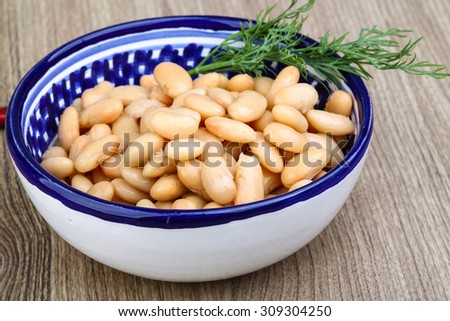 White canned beans with dill branch on the wood background