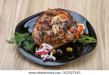 Roasted pork knee with dill and rosemary on the wood background