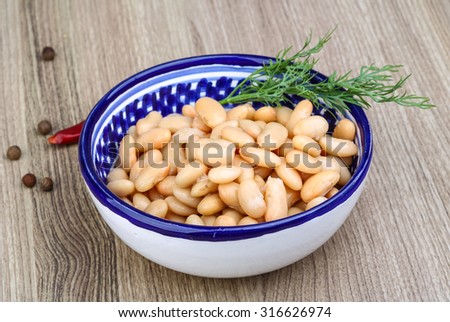 White canned beans with dill branch on the wood background