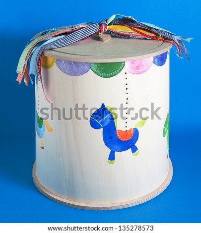 wooden box for baptismal clothes with horse and ribbons on blue background