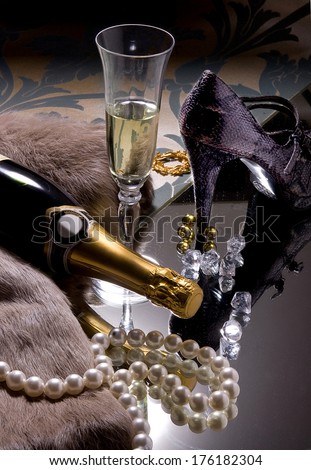 composition of the glass and bottle of champagne, high-heel shoe, necklace of pearls, diamonds and fur scarf