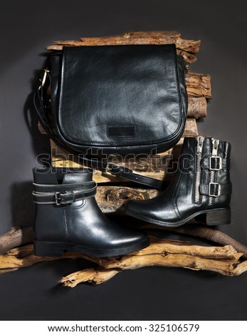 a elegant women leather bag with two leather boots on woods,on woods in plan