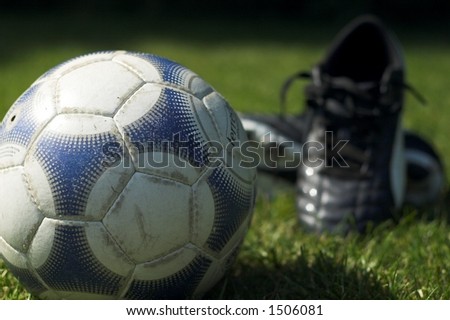 Soccer ball in foreground in focus with soccer boots out of focus in background