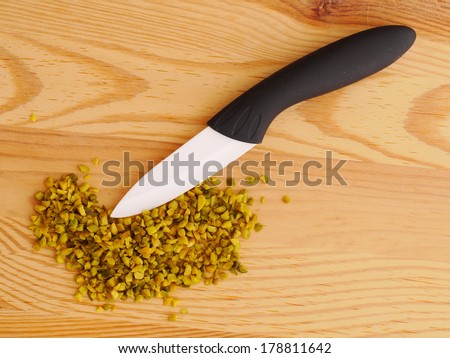 A white ceramic knife sits on a wooden chopping board