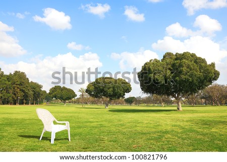 Lonely white chair on the green meadow of the city park