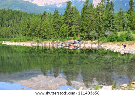 Mountain lake with a smooth water and tourist kayaks on the shore. Jasper National Park. Alberta, Canada