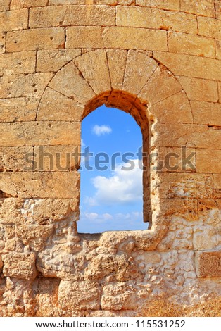 Arch window of old sand stone wall and blue sky