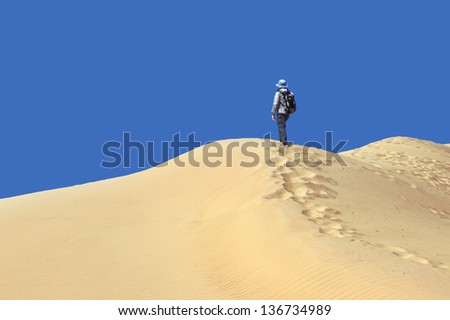 Sandy desert and man standing at a dune top