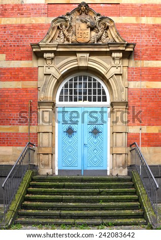 Blue wooden glass door of an old red brick classical building. Renaissance style building - entrance door and stairway. Europe. Architectural theme.