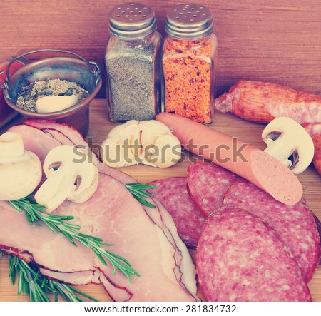 Various delicious low fat meats, salamis and sausages with raw fresh mushrooms and herbs. Mediterranean cuisine.Close up. Selective focus. Image done in vintage retro instagram style