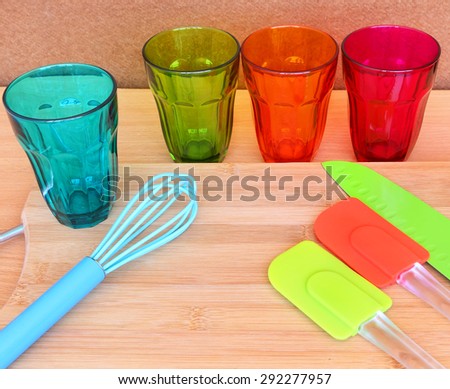 Colorful drink glasses and  kitchen utensils on wood background