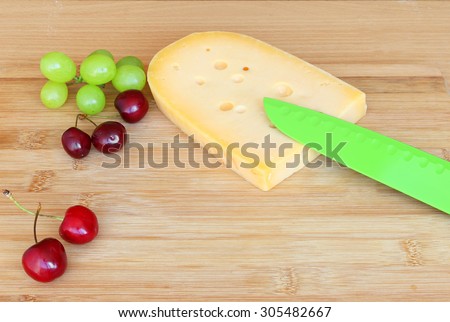 Cheese and berry fruits ( sweet cherry and grapes) on the wood cutting board. Healthy food for breakfast or snack