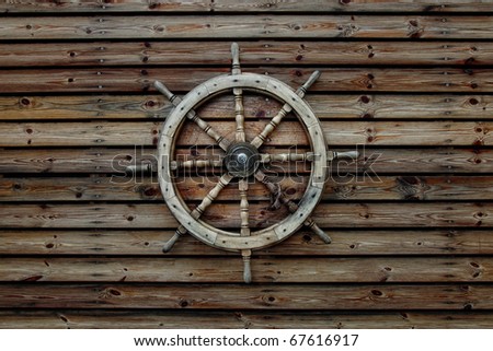 Steering wheel of the ship on a wooden wall of the old house