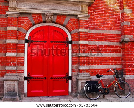 Red bicycle near a red brick wall and a red door