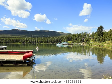 Boats on smooth water of mountain lake (Maligne lake. Jasper National Park, Alberta, Canada)