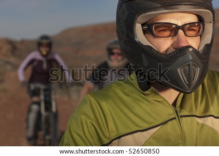 A group of mountain bikers is wearing protective eyewear and a helmets in a desert setting. Horizontal shot.