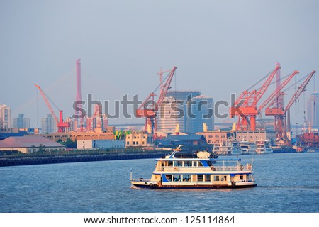 Boat in Huangpu River with Shanghai urban architecture and cargo crane