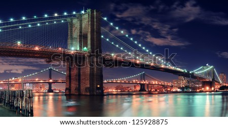 Brooklyn Bridge over East River at night in New York City Manhattan with lights and reflections.