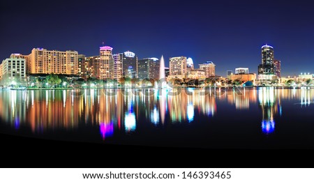 Orlando downtown skyline panorama over Lake Eola at night with urban skyscrapers and clear sky.