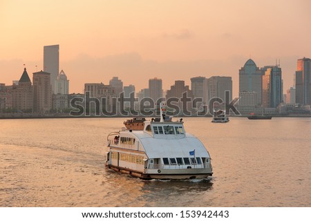 Boat in Huangpu River with Shanghai urban architecture at sunset