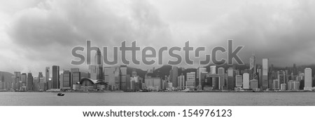 Urban architecture in Hong Kong Victoria Harbor with city skyline and cloud in the day in black and white.