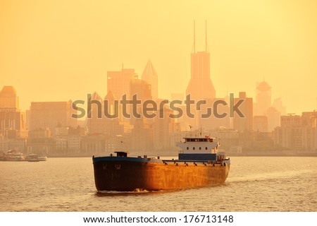 Boat in Huangpu River with Shanghai urban architecture at sunset