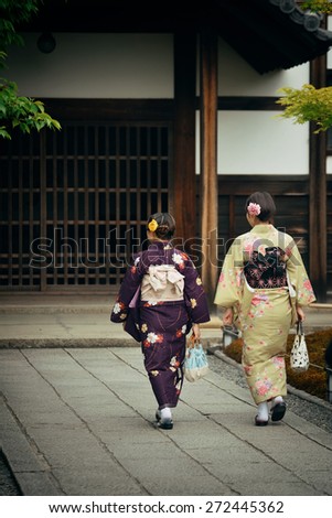 Japanese woman in traditional costume in shrine with historical building in Kyoto, Japan.