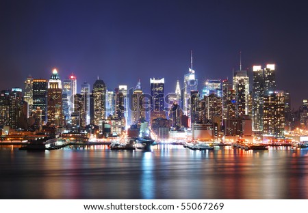Mordern city night scene. New York City Times Square Manhattan Skyline at night panorama over Hudson River with reflection.