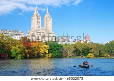 New York City Manhattan Central Park panorama in Autumn lake with skyscrapers and colorful trees over with reflection with boat.
