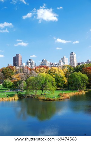 New York City Central Park in Autumn with Manhattan skyscrapers and colorful trees over lake with reflection.