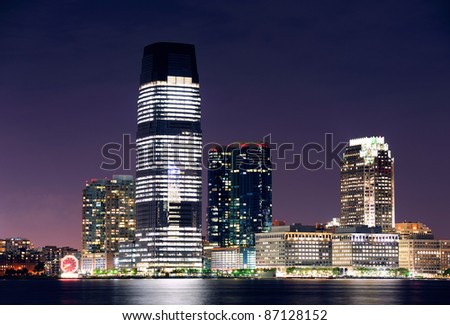 Jersey City skyline with skyscrapers at night over Hudson River viewed from New York City Manhattan downtown.