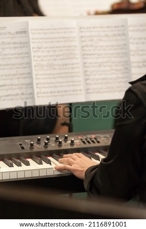 musician playing on muzical synthesizer with paper music notes in blurry background. Imagine de stoc © 