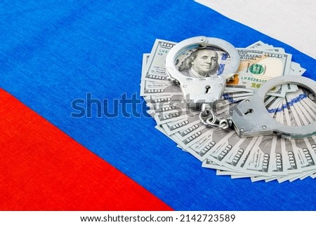 silver metal police handcuffs over paper dollar banknotes of United States of America over national flag of Russian Federation, concept of foreign currency prohibition Photo stock © 