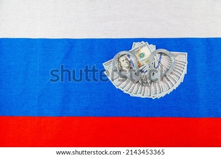 silver metal police handcuffs over paper dollar banknotes of United States of America over national flag of Russian Federation, concept of foreign currency prohibition in high angle view Photo stock © 
