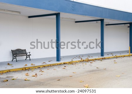 Lone weathered bench remains after store closing during a bad economy