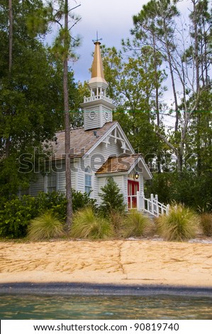 Small church hidden among pine trees on a sandy beach with red entry doors