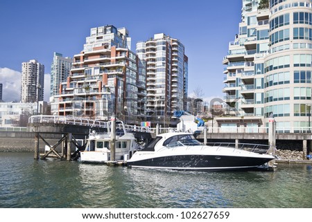 Luxury boats  in front of highrise apartment and condo buildings on the waterfront of Vancouver, British Colombia.