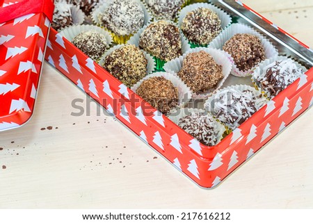Homemade chocolate truffles with different coatings such as coconut, crushed almonds or hazelnuts or walnuts. Each placed in a decorative cup and placed in a Christmas box.