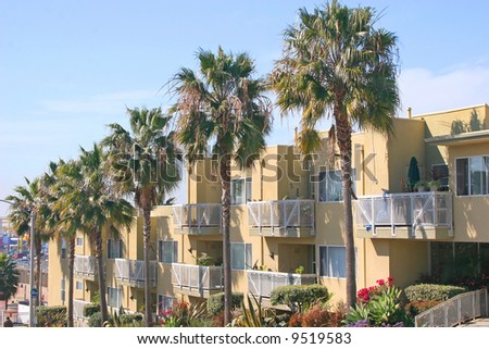 An apartment building with a stucco finish or possible motel surrounded by palm trees.