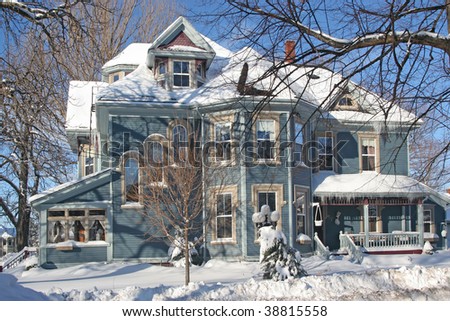 A large Victorian home covered with snow.