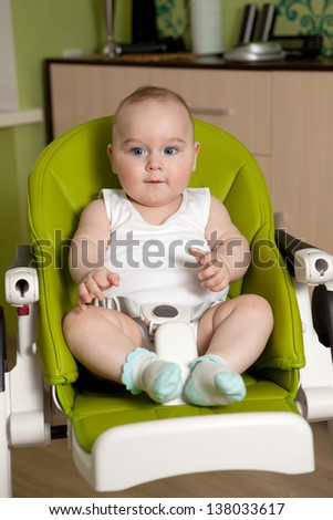 Eight month old baby sitting in a special chair for feeding