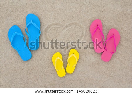 blue, red, yellow flip flops and heart on the beach