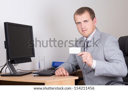 young business man sitting in office and showing his visiting card