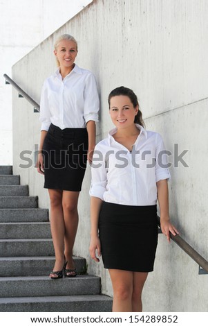 two young attractive business women posing on stairs