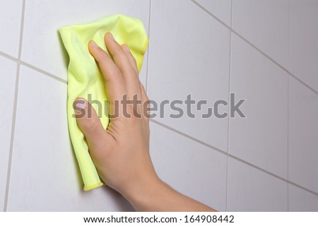 male hand with rag cleaning the bathroom tiles