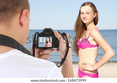 photographer with camera taking picture of young beautiful woman on the beach